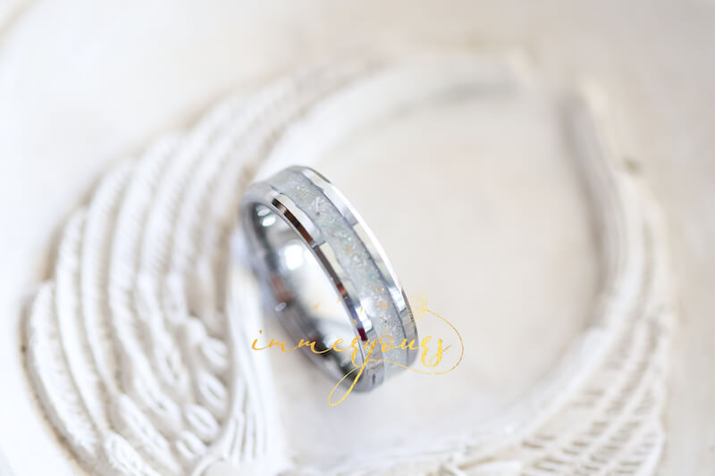 A tungsten memorial ash ring with a subtle, pearl-coloured inlay. The ring features delicate speckles of white and light grey, giving it a serene and timeless look.