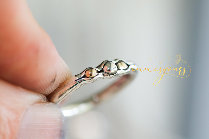Ash Infused Silver ring with small stones held by a hand against a blurred background